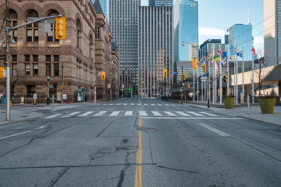 View straight down empty wide street in downtown Toronto, Canada with stoplights during Covid-19 pandemic.